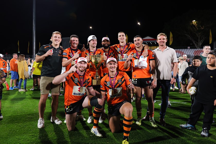 Melbourne Storm's 2023 players Alec MacDonald, Jonah Pezet, Cole Geyer, George Jennings, Kane Bradley, Jordan Grant and Tristan Powell with Development Coach Todd Lowrie celebrate the Brisbane Tigers winning the grand final.